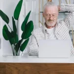 Proprietário de uma pensão a analisar estatísticas de reservas num computador portátil.