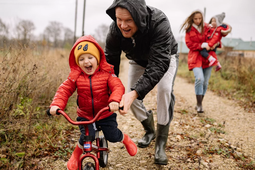 A parent teaches a child to ride a bicycle on vacation at a family-friendly facility.
