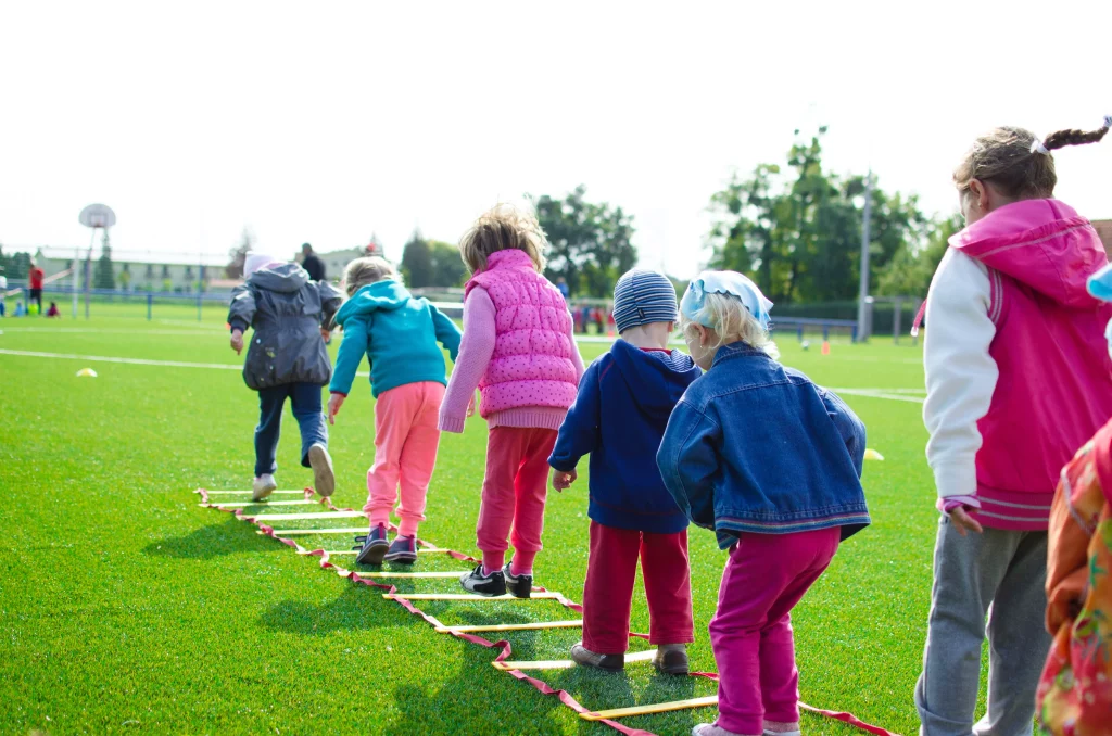 A group of children playing on the grass by a vacation home with a garden and attractions.